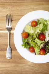 A dish of classic side salad with fork on a wooden table background