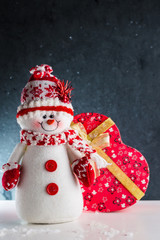 
White Christmas snowman stands on a snowy background on New Year's Eve
