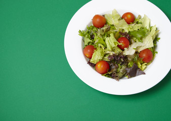 A dish of classic side salad on a green background with blank space at side