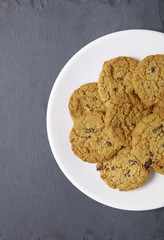 Aerial view of a plate full of freshly baked oatmeal and raisin cookies on a rustic slate background