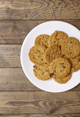 Aerial view of a plate full of freshly baked oatmeal and raisin cookies on a rustic wooden background