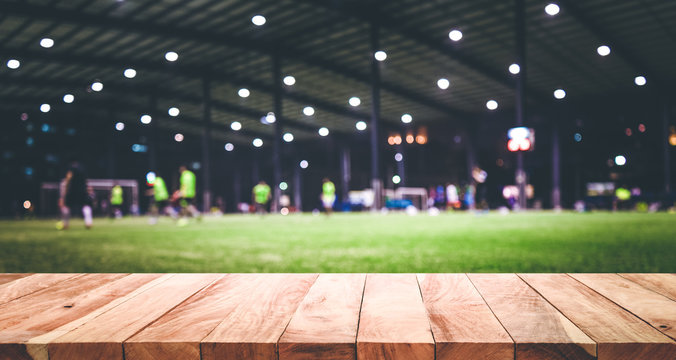 Fototapeta Wood table top with blur football (soccer) field background.