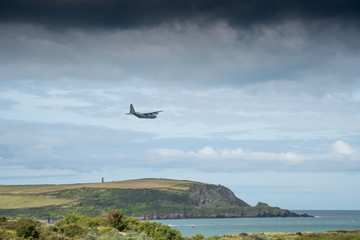Camel estuary at Daymer Bay in Cornwall with a military transport plane in low-level flight.