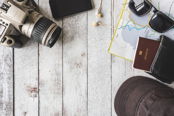 Top view of Camera with cap,sunglasses,wallet,smart phone,map and passport on wooden table