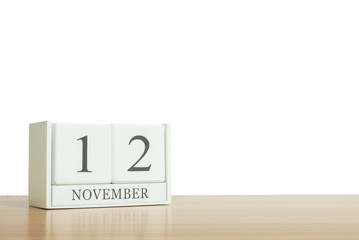 Closeup surface white wooden calendar with black 12 november word on blurred brown wood desk isolated on white background with copy space , selective focus at the calendar