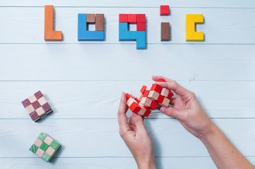 Logic background. The concept of logical thinking. The word of logic of multi colored wooden blocks on a wooden background. Hands holding wooden cubic. 