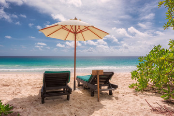 Two beach lounge chairs under umbrella on beach - vacation holidays background 