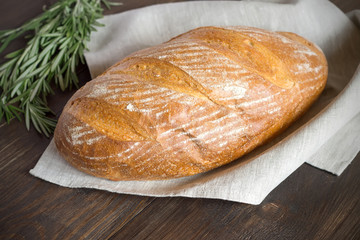 Fresh homemade bread with crust on a dark wooden table.