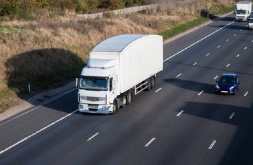 Road transport. White lorry in motion on the motorway