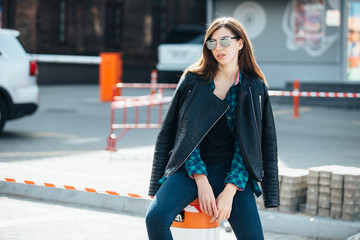 Brunette girl in rock black style, standing outdoors in the city street