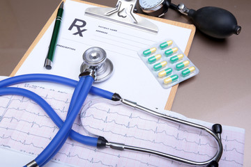 Stethoscope head and silver pen lying on cardiogram  clipboard pad. Cardio therapeutist assistance, physician make cardiac physical, pulse beat measure document, arrhythmia idea, pacemaker concept