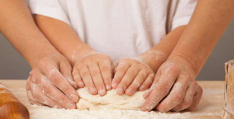 Obraz na płótnie Canvas children's hands and the hands of his mother and knead dough tog