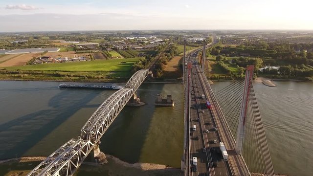 Traffic on large cable bridge over river Waal in the Netherlands, aerial footage. Camera flies over and across bridge.