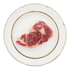 Raw rib-eye steak on plate, isolated