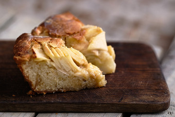 Slice of a french apple cake with vanilla and rum on a cutting board. Wooden background. Horizontal