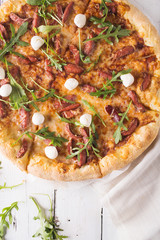 Thick-crust pizza with hunting sausages, mozzarella cheese on a white wooden background