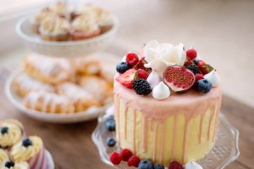 Cake with various berries and meringues on a stand.