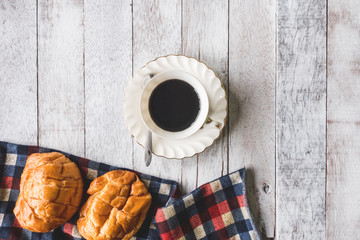 Top view of Coffee cup with bread and tablecloth on wooden table