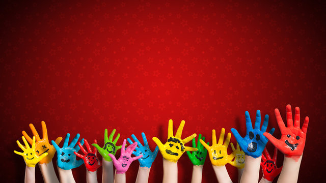 viele angemalte Kinderhände mit Smileys vor weihnachtlichem Hintergrund