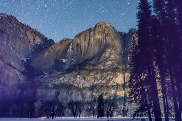 Upper Yosemite Falls moonlit under a star filled winter Sky