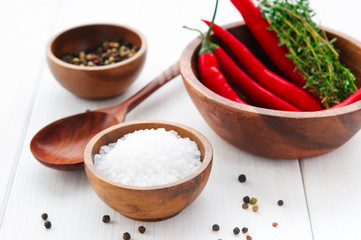 Salt, pepper, chili and thyme in bowls on white rustic wooden table