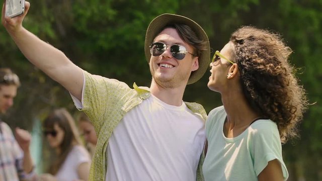 Young man in hat and his biracial girlfriend taking selfie and laughing, relax