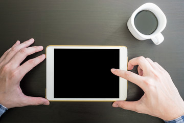 Top view of Male hands using Tablet, Cup of coffee on the desk.