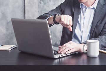 Close up of Businessman working on the office desk and checking time on his wrist watch 