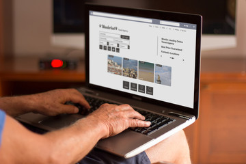 Fototapeta na wymiar Cropped image of a senior man using his laptop at home with trav