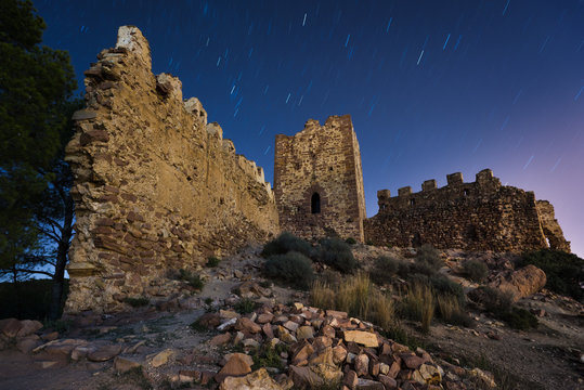 Ruins of castle on night with startails sky.