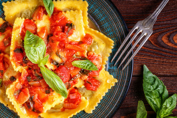 Ravioli with tomato sauce and basil on dark background.