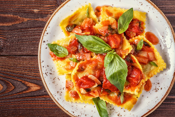 Ravioli with tomato sauce and basil on dark background.
