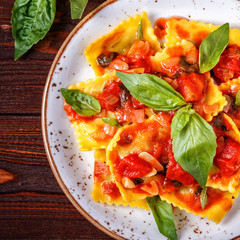 Ravioli with tomato sauce and basil on dark background.