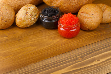 Red and black caviar in a jar with bread