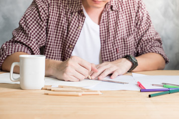 Close up of A man drawing on papers on the wooden table.