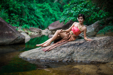 Beautiful girl with Thai dressing was playing water in the river.