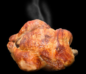 Smoking hot roasted chicken isolated on black background