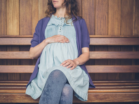 Pregnant woman sitting on bench in shelter