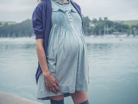 Young pregnant woman by river in small town