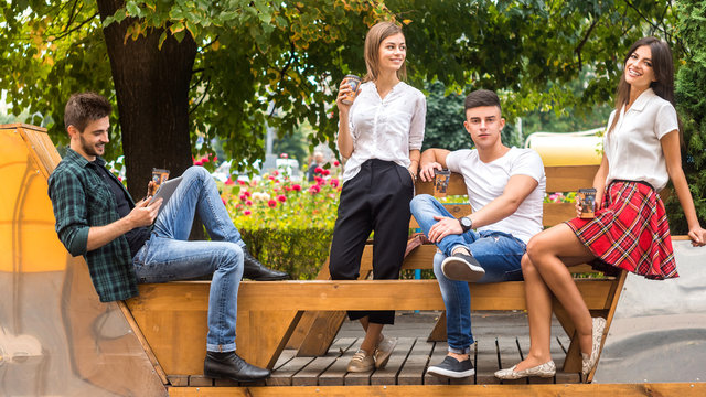 Students life. Low angle view of cheerful young people communicating while sitting outdoors.