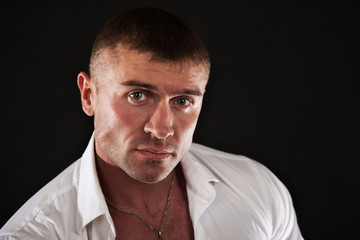 Closeup of young man looking serious. Studio shot. Dark background.