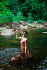 Beautiful girl with Thai dressing was playing water in the river.