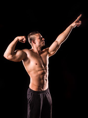 Fototapeta na wymiar young bodybuilder man pointing isolated on black background