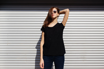 Portrait of girl in rock black style, standing outdoors in the city against the silver metal urban wall