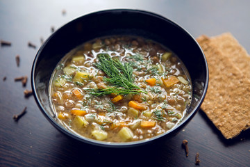 lentil soup in a black bowl on dark wooden table