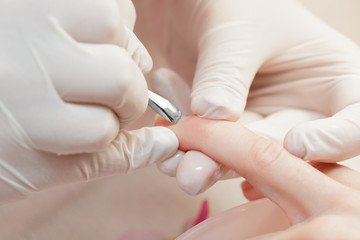 Manicurist uses  professional manicure tool.