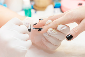 beautician applying Polish nails to women 