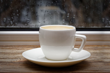 Closeup white ceramic cup on wooden windowsill