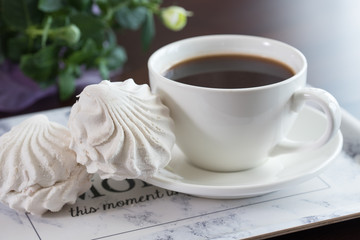 Delicious snacks. Cup of coffee with white zephyr, marshmallow on wooden table.