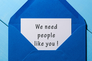 We Need People Like You - text in letter at open blue envelope on workplace. Business concept